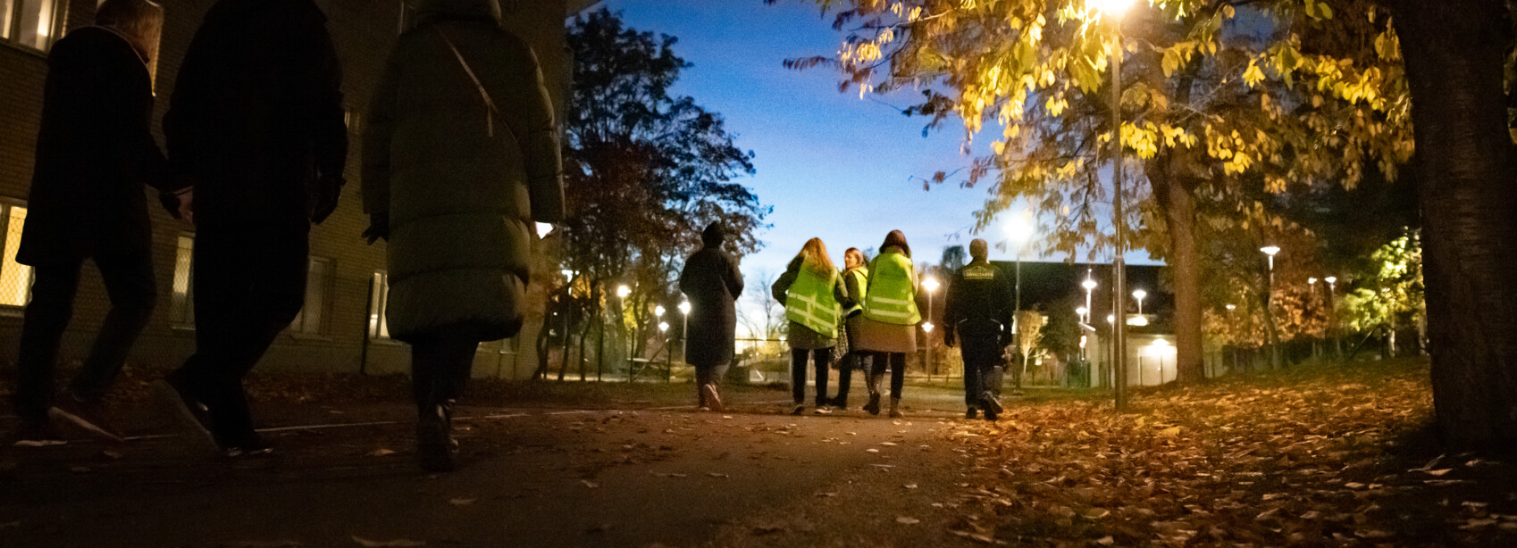 hyresgsgäster och medarbetare från förvaltaren prommenerar i mörkret för att identifiera nödvändiga trygghetsåtgärder i området