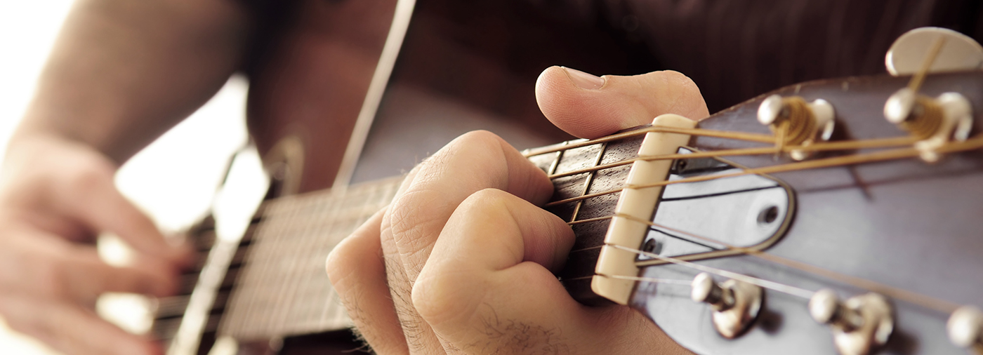 en person spelar på en brun gitarr