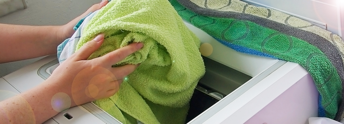 färglada handdukar placeras i tvättmaskin