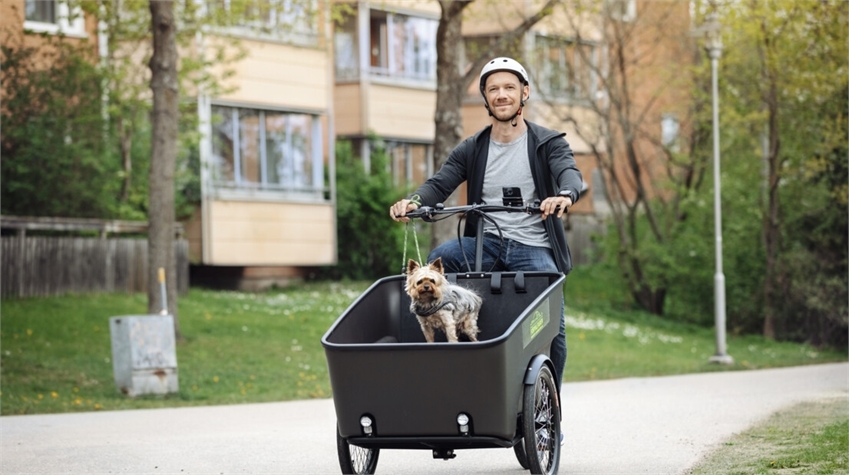 Om projektet - Man cyklar lådcykel med en liten hund i