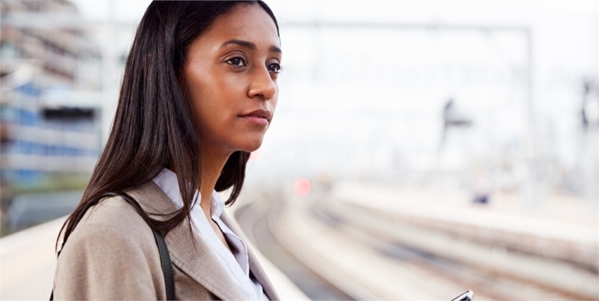 Vad är MoBo 3? - En kvinna på en tågperrong håller i en mobil och blickar ut över spåren.