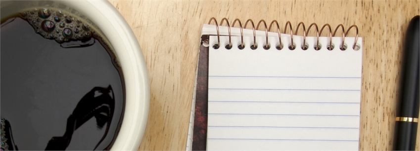 Välkommen till samråd - En kopp med svart kaffe, ett anteckningsblock och en bläckpenna på ett bord. 