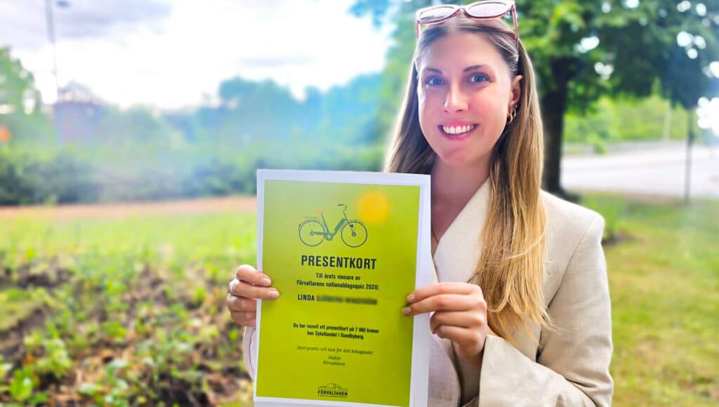 Linda håller leende upp sitt presentkort där det står att hon vunnit quiz och därmed cykel.