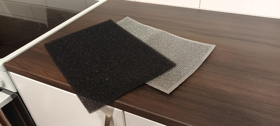 Foto av svart polyesterfilter och metallfilter som ligger på en köksbänk.